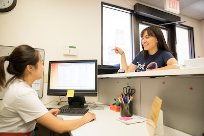 A student speaks to another student at a front desk